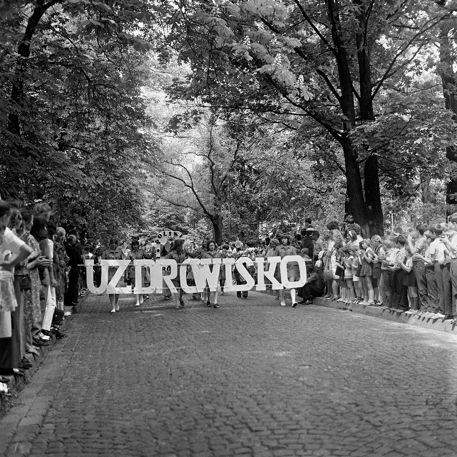 Stare czarno-białe zdjęcie przedstawiające tłum oglądający wyścig.