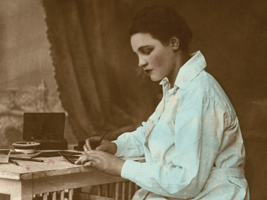 Stare zdjęcie kobiety piszącej przy biurku.