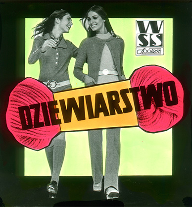 Grafika reklamowa. Na zielonym tle widać dwie uśmiechnięte i patrzące na siebie idące kobiety. Mają długie ciemne włosy. Kobieta po lewej stronie ubrana jest w sukienkę i podkolanówki. Kobieta po prawej stronie ubrana jest w spódnicę, bluzkę i sweter. Zdjęcie kobiet jest czarno-białe. Na środku znajduje się rysunek różowej włóczki. Na rysunku jest czarny napis “dziewiarstwo”. W prawnym górnym rogu czarny napis WSS Społem. Grafika otoczona jest czarną ramą. Link do wyników wyszukiwania hasła reklama