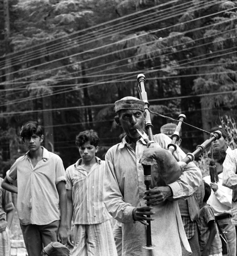 Mężczyzna grający na kobzie i słuchający go mężczyźni na ulicy. Link do wyników wyszukiwania hasła muzycy i kapela