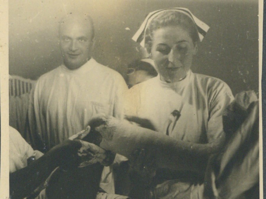 Stare zdjęcie przedstawiające pielęgniarkę zakładającą pacjentowi gips.