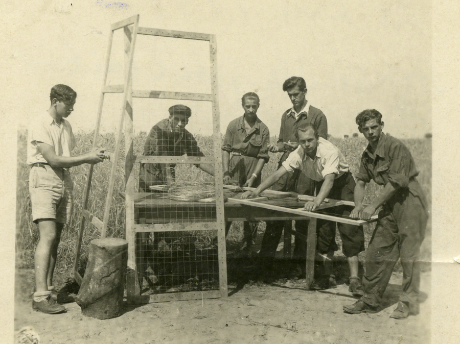 Grupa mężczyzn stojących na polu z drewnianą ramą.