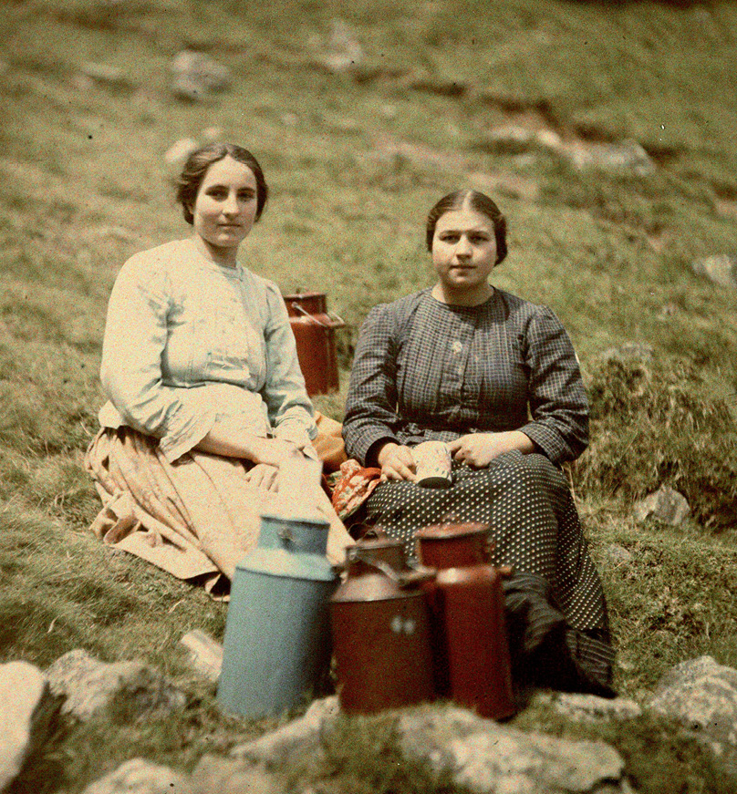 Dwie młode kobiety siedzące na porośniętej roślinnością skale. Link do wyników wyszukiwania hasła “górale”