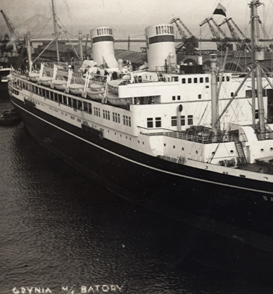 Czarno-białe zdjęcie. Na pierwszym planie statek pasażerski “Batory”. Statek stoi w porcie. Na pokładzie statku widać łodzie ratunkowe, kominy i maszty. W tle widoczne dźwigi portowe i inne statki.Link do wyników wyszukiwania hasła Gdynia